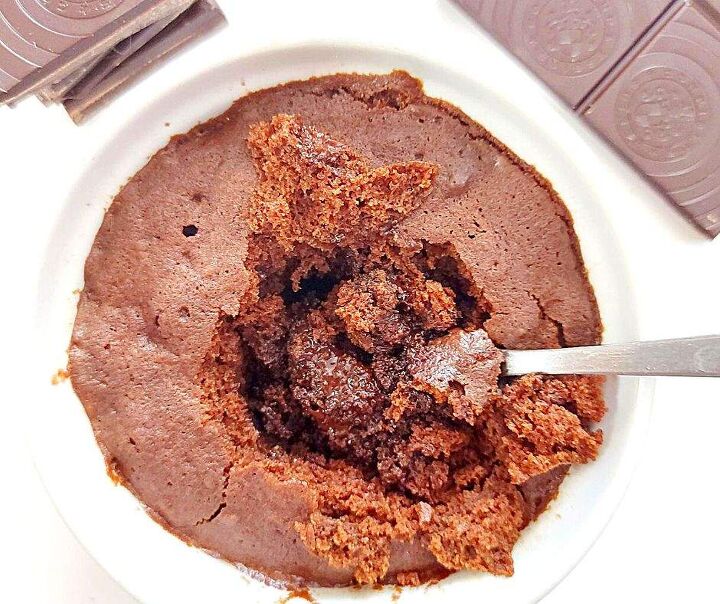 gooey chocolate mug cake that chocolate lovers need in their life, Gooey chocolate mug cake with a stack of chocolate squares and a chocolate bar on the side