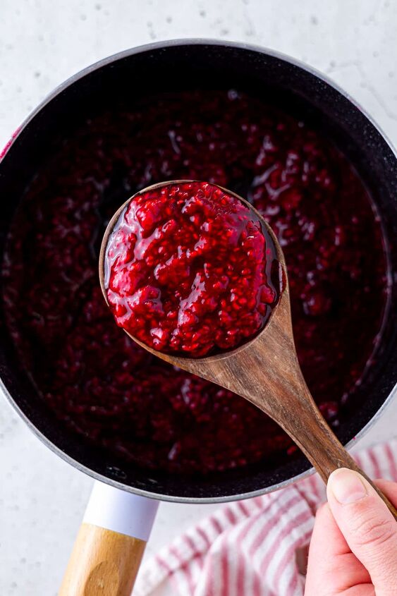 how to make raspberry compote, A saucepan and wooden spoon filled with compote