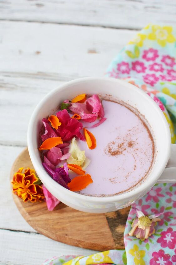 warm and cozy fairy flower moon milk, Pink milk in a mug topped with flowers and swirls of cinnamon on a table