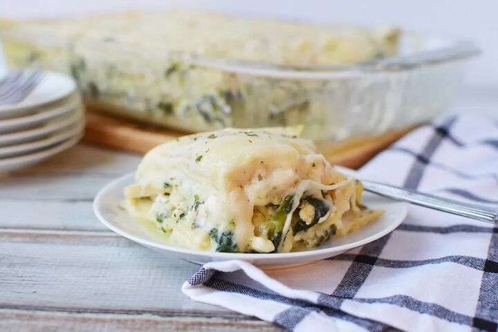 creamy chicken and spinach lasagna recipe, Spinach and chicken lasagna on a plate with the baking dish behind it