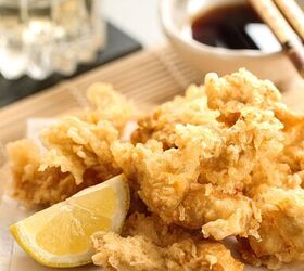 japanese chicken tempura with light and crispy batter, Chicken Tempura with a slice of lemon on a wooden board with a bowl of ponzu dipping sauce and chopsticks in the background