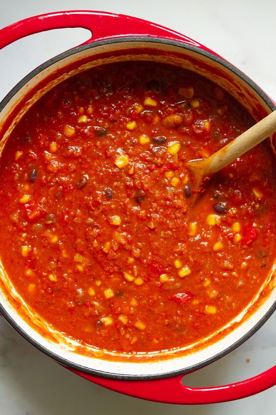 easy spicy mexican chilli bean soup with corn, A red dutch oven containing the finished soup with corn added