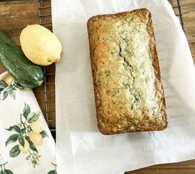 the best lemon zucchini bread, bread on a cooling rack on table with lemon and zucchini