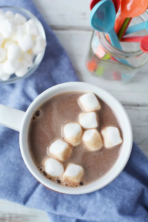 extra creamy homemade hot chocolate recipe, Cup of hot cocoa on a blue napkin with colorful spoons