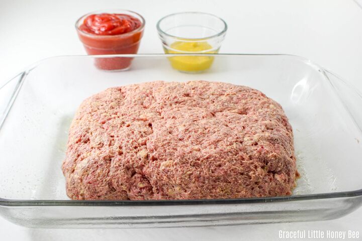 old fashioned meatloaf recipe with crackers, Raw meatloaf in glass baking dish with two small glass dishes of ketchup and mustard in the background