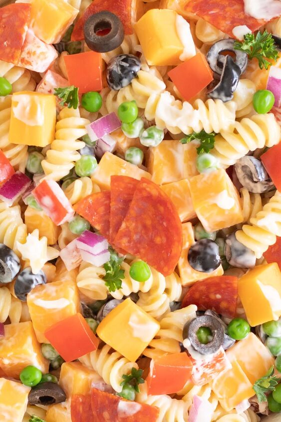 the throwback creamy pasta salad everyone will rave about, full photo filled with spiral pasta salad with pepperoni quarters cheese cubes parsley black olives red onions