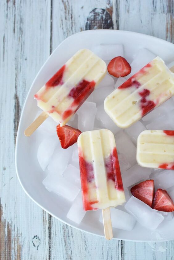 creamy and delicious cheesecake popsicle recipe, Strawberry popsicles in a dish with ice and fresh sliced strawberries
