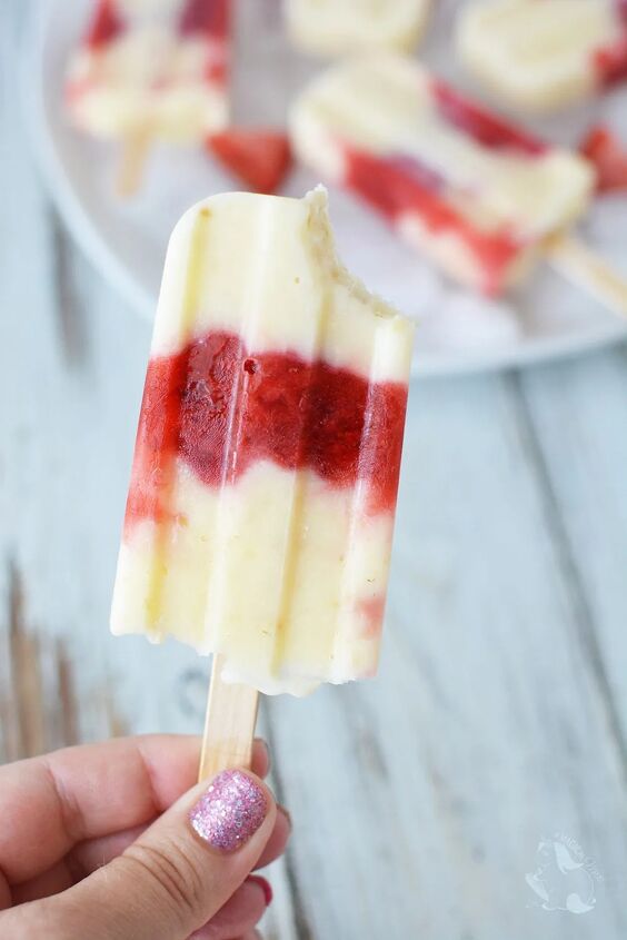 creamy and delicious cheesecake popsicle recipe, Holding a strawberry cheesecake pop with a bite taken out of it