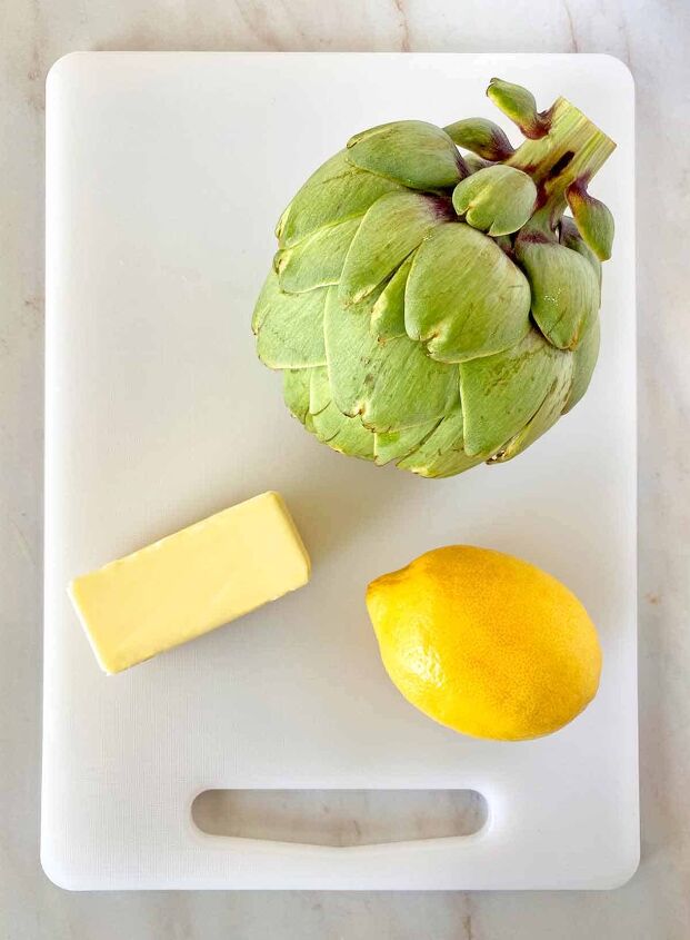 how to microwave an artichoke, An artichoke a stick of butter and a lemon on a cutting board