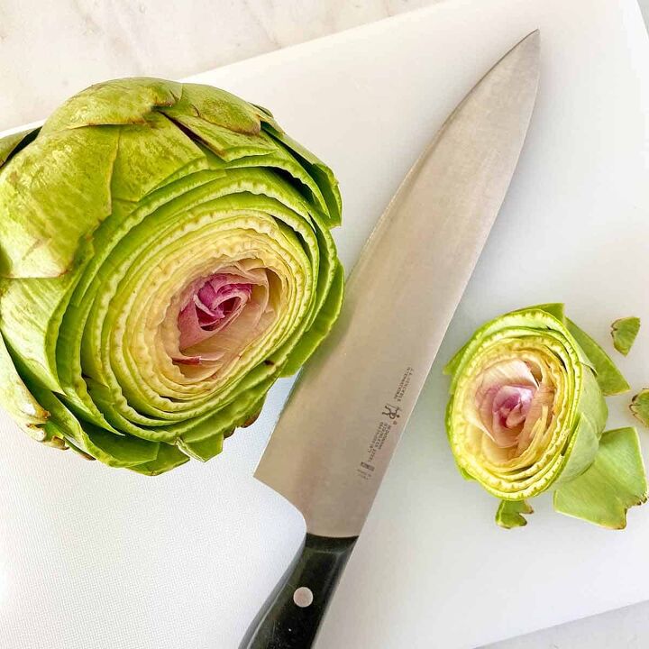 how to microwave an artichoke, An artichoke with the top sliced off and a knife on a cutting board