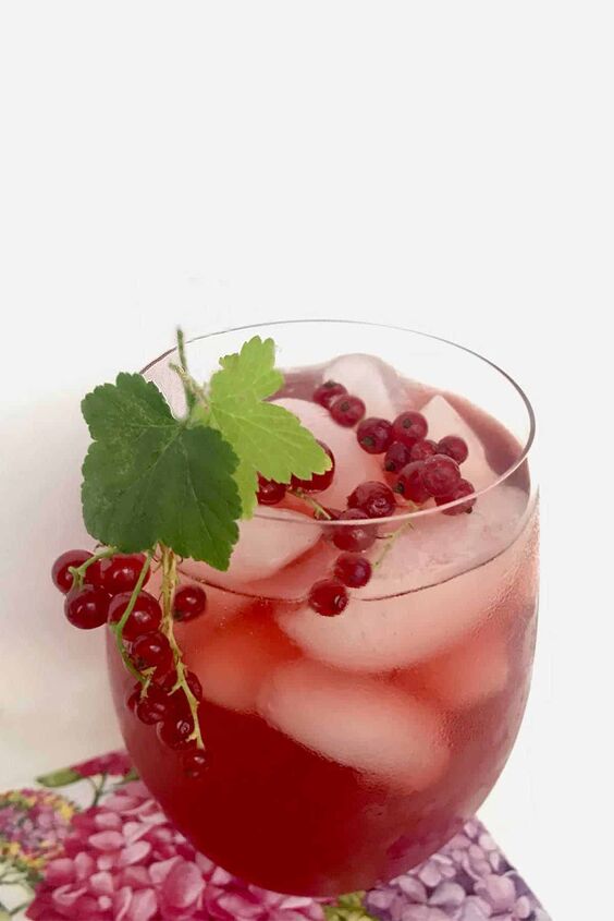 A glass of honey iced tea with red currants and currant leaves