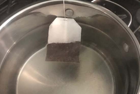 Making honey iced tea with tea bags and boiling water in a saucepan