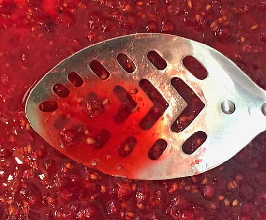 crushing red currants with a metal spoon to extract the juice