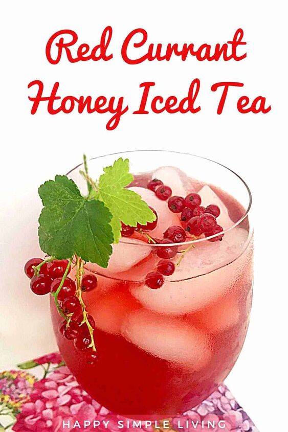 A glass of red currant honey iced tea garnished with currant leaves and berries