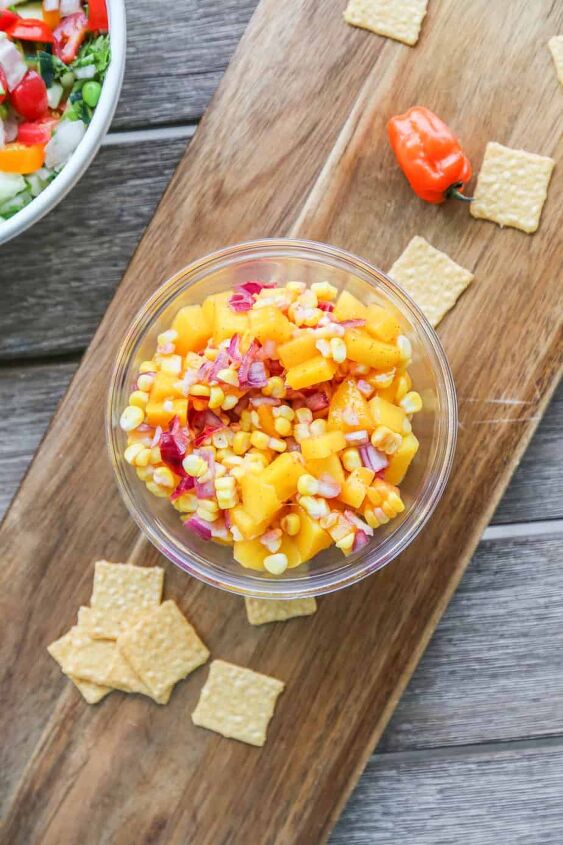 mango corn salsa, bowl of mango corn salsa with chips and peppers on the table