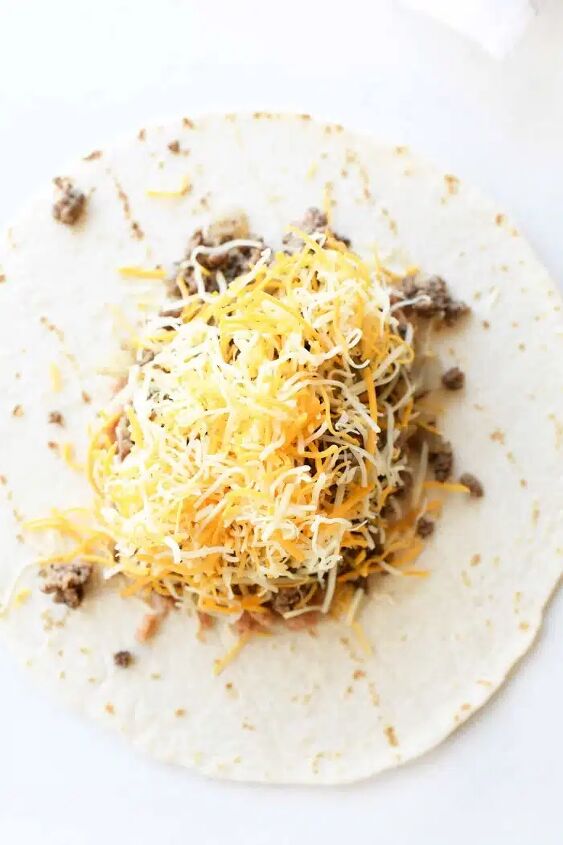 how to make beef chimichanga quick and easy, Open flour tortilla topped with ground beef refried beans and shredded cheese