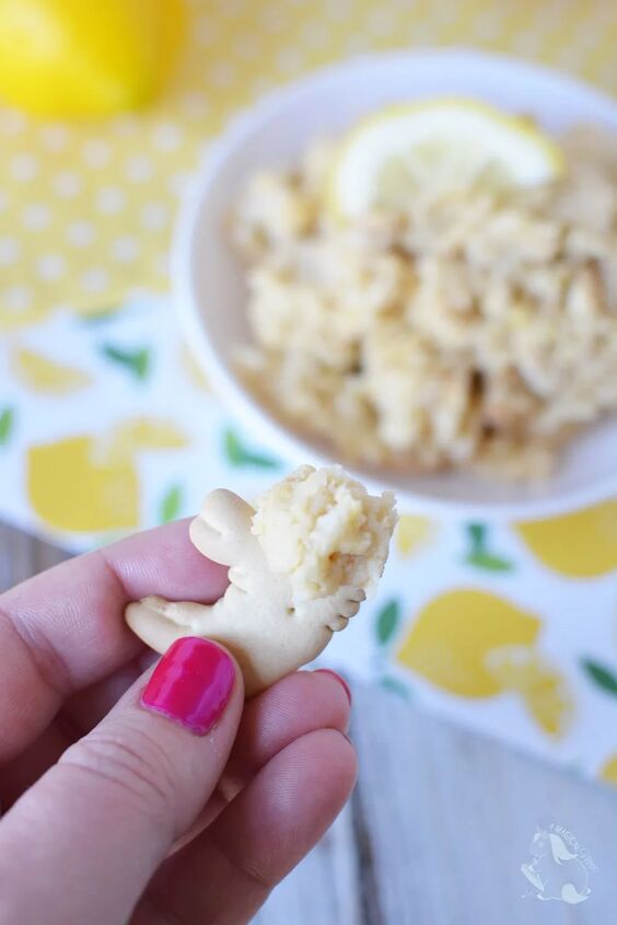 light and fluffy lemon cookie dough dip, Holding an animal cracker with cookie dough on it with the bowl of cookie dough dip in the background