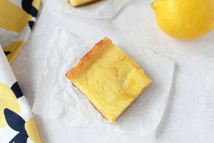 lemon curd cheesecake bars, Lemon Swirled cheesecake square on a piece of white parchment paper
