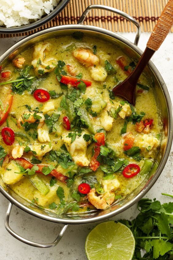 easy 30 minute prawn thai green curry, A silver coloured bowl of curry on a white background with rice cilantro and a slice of lime