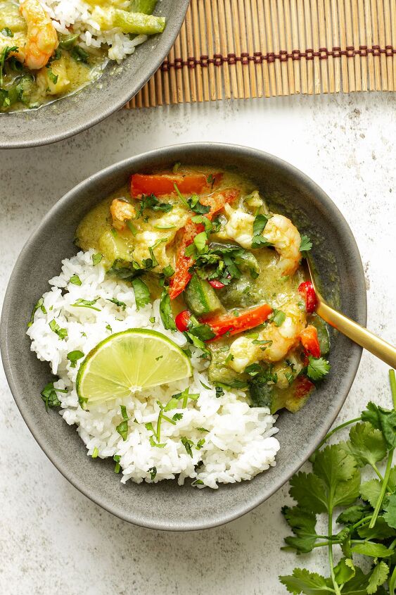 easy 30 minute prawn thai green curry, A grey bowl of curry rice and a slice of lime and cilantro on a white background