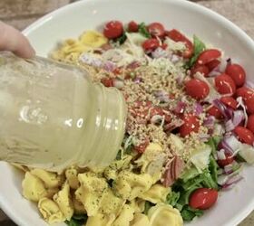 italian tortellini salad, adding dressing to salad ingredients in a white bowl