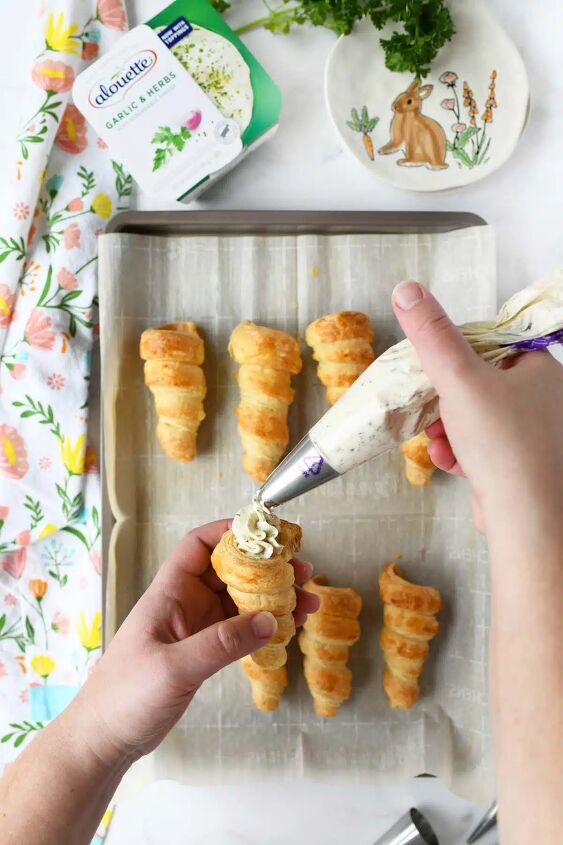 carrot shaped puff pastry appetizers, A hand piping a puff pastry carrot