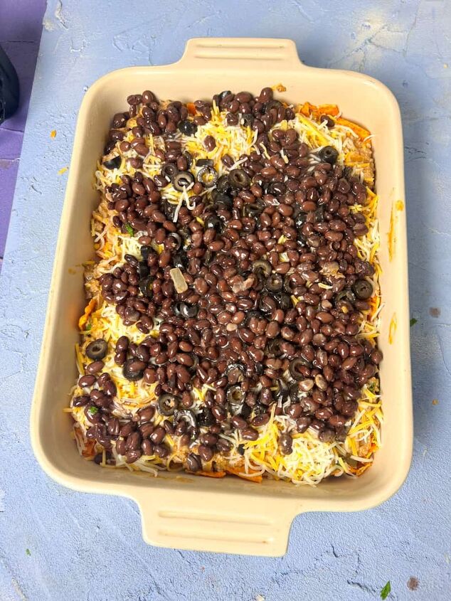 dorito casserole with ground beef, black beans on cheese and beef layers in a casserole dish