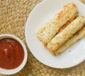 air fryer mozzarella sticks on a plate with a bowl of marinara sauce