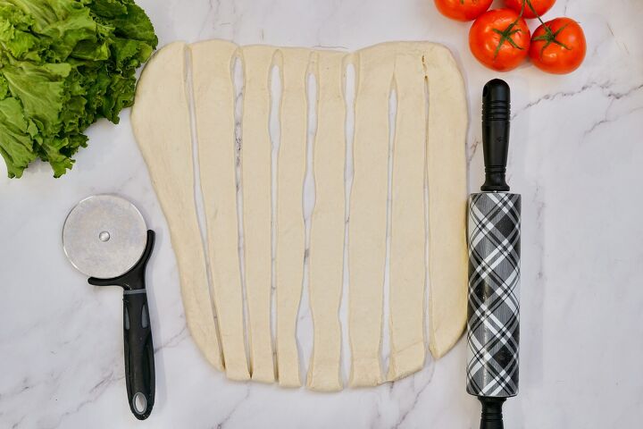 Cutting rolled out pizza dough into strips
