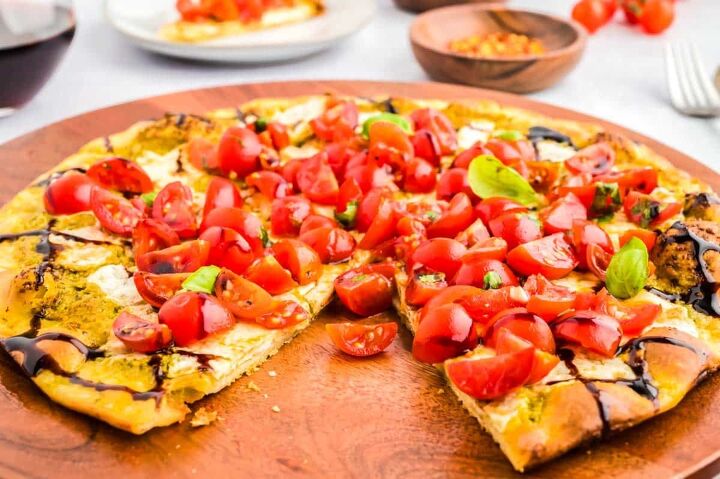 easy bruschetta pizza recipe, Bruschetta Pizza on a wooden cutting board with one piece cut out