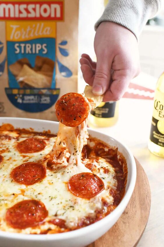 game day pizza dip, A man dipping a chip in cheesy pepperoni dip