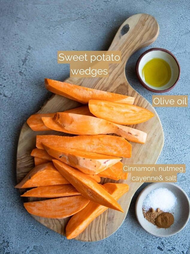 air fryer sweet potato wedges, uncooked sweet potato wedges on a wood board net to a small bowl of olive oil and seasonings