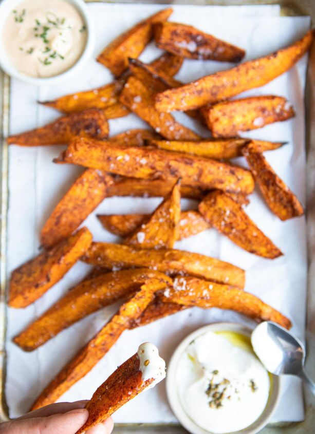 air fryer sweet potato wedges, woman holding a sweet potato fry dipped in sauce