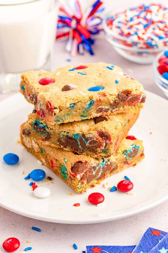 easy fourth of july cookies with m ms, Three chocolate chip cookie squares on a white plate that has red white and blue M M s