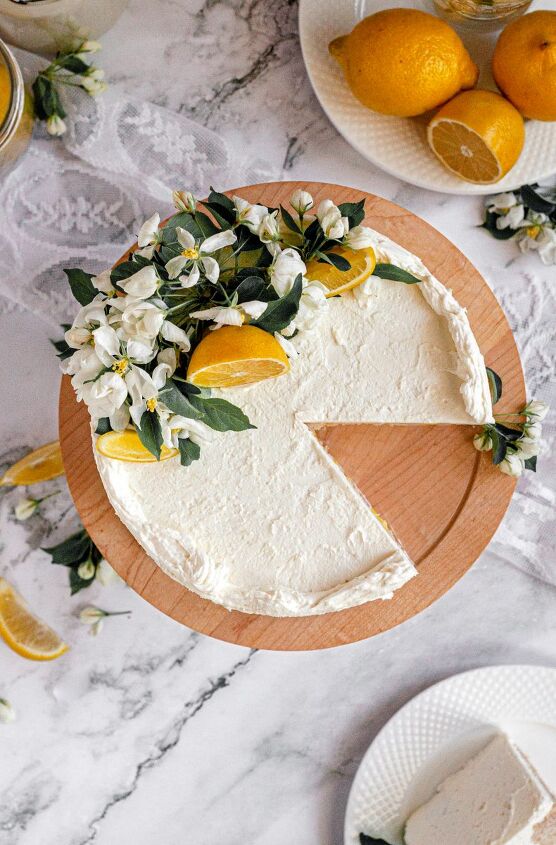 gluten free lemon cake vegan, A gluten free and vegan lemon cake covered in bright white cream cheese frosting fresh lemon curd filling and topped with white apple blossoms and lemon slices