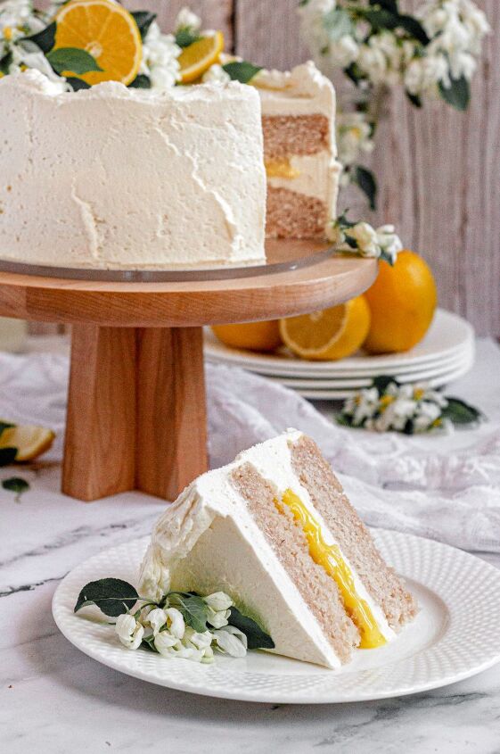 gluten free lemon cake vegan, A gluten free and vegan lemon cake covered in bright white cream cheese frosting fresh lemon curd filling and topped with white apple blossoms and lemon slices