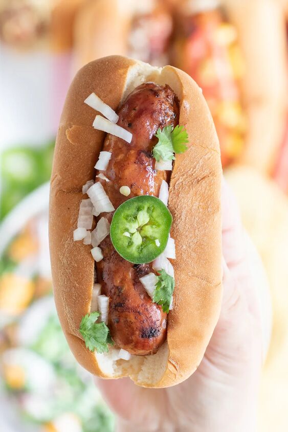 how to make classic pea salad, up close view of grilled cajun sausage topped with chopped onions jalape o slices and cilantro