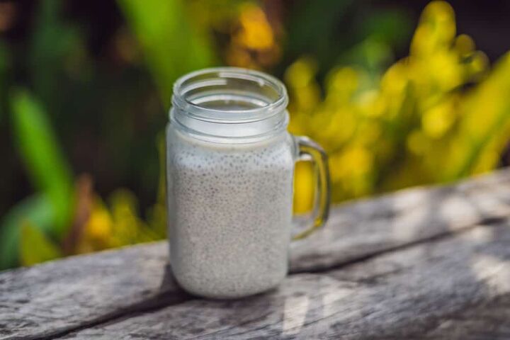 Healthy layered dessert with chia pudding in a mason jar on rustic background