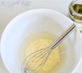 classic creamy german pasta salad nudelsalat, bowl with mayonnaise and pickle juice with wire whisk and jar of gherkins