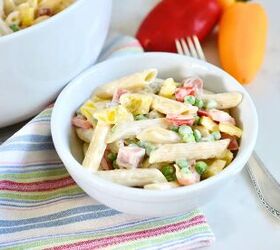 classic creamy german pasta salad nudelsalat, small bowl with classic German pasta salad on kitchen counter with fork bell peppers and tea towel