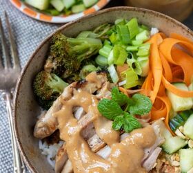 thai chicken rice bowls with peanut sauce, A bowl filled with rice roasted broccoli carrots and diced cucumber There s sliced grilled chicken and a peanut sauce drizzled on top There s a fork next to the bowl and a small bowl filled with diced cucumber in the background