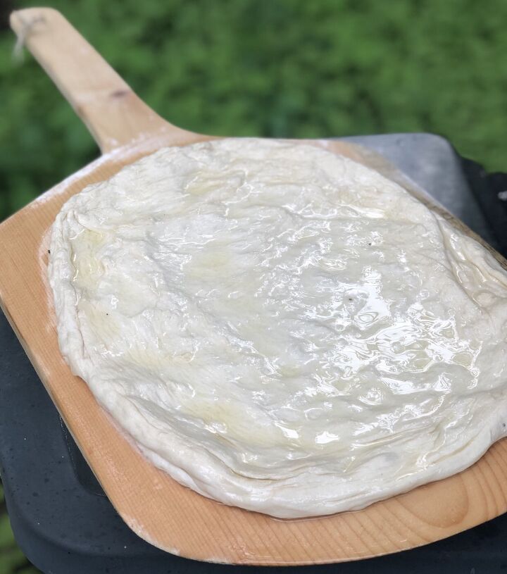 easy summer squash grilled pizza, Image raw pizza dough that s been stretched into a rectangle shape and covered with olive oil before placing on the grill It s on a pizza paddle