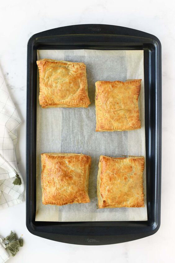 easy cheesy beef onion potato puff pastry pockets, Golden brown puff pastry pockets on a blue baking sheet
