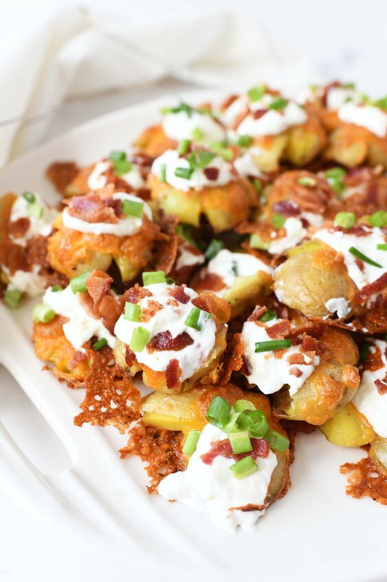 easy oven baked loaded smashed baby potatoes, Loaded smashed potatoes with cheese sour cream and bacon on a white platter