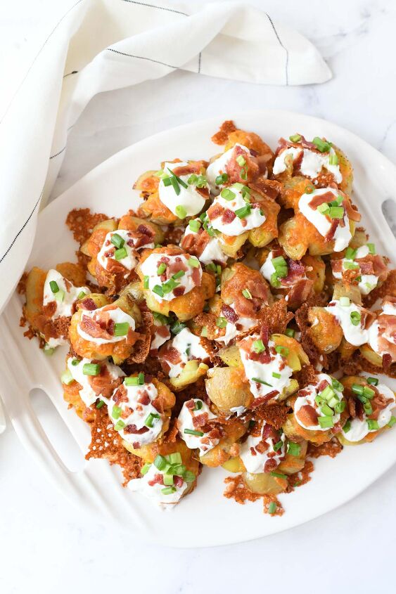 easy oven baked loaded smashed baby potatoes, Loaded smashed potatoes on a white plate with a white napkin
