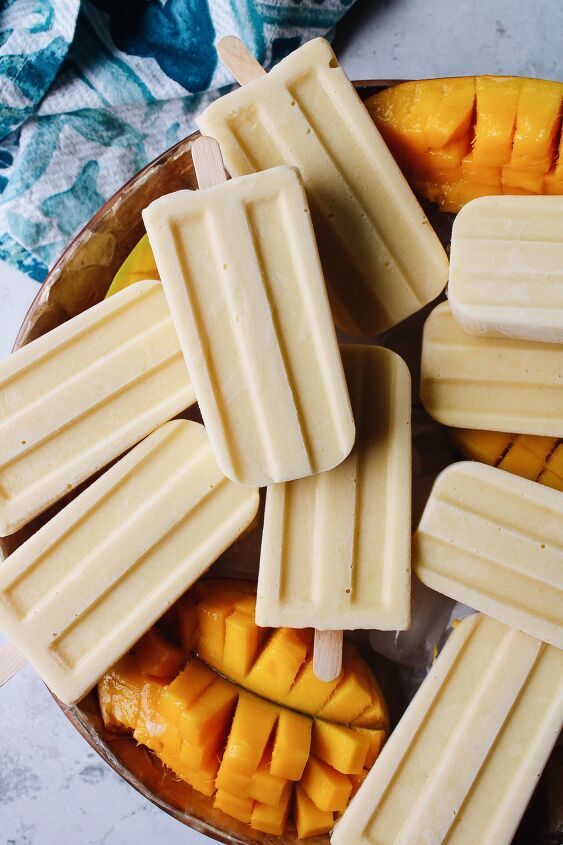 mango popsicles, mango popsicles on a bowl of ice with cut mango scattered around