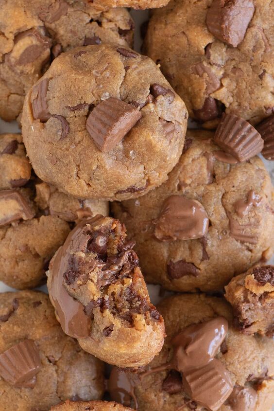 the peanut butter cup cookies recipe you ll make again and again, gooey peanut butter cup cookies up close one cookie with a bite taken out of it revealing lots of melty chocolate chips inside
