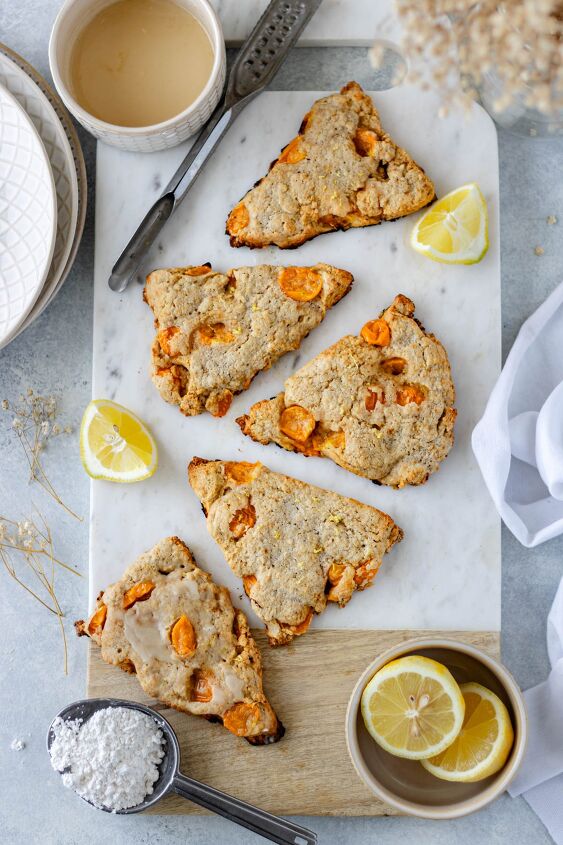 cape gooseberry scones with lemon, Five Cape Gooseberry Scones with Lemon resting on a marble cutting board and surrounded by lemon wedges powdered sugar and an old fashioned microplane