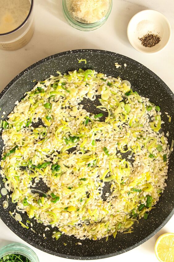 smoked haddock and leek risotto easy one pan recipe, Saut d leeks and spring onion scallions with the rice added in a dark coloured pan