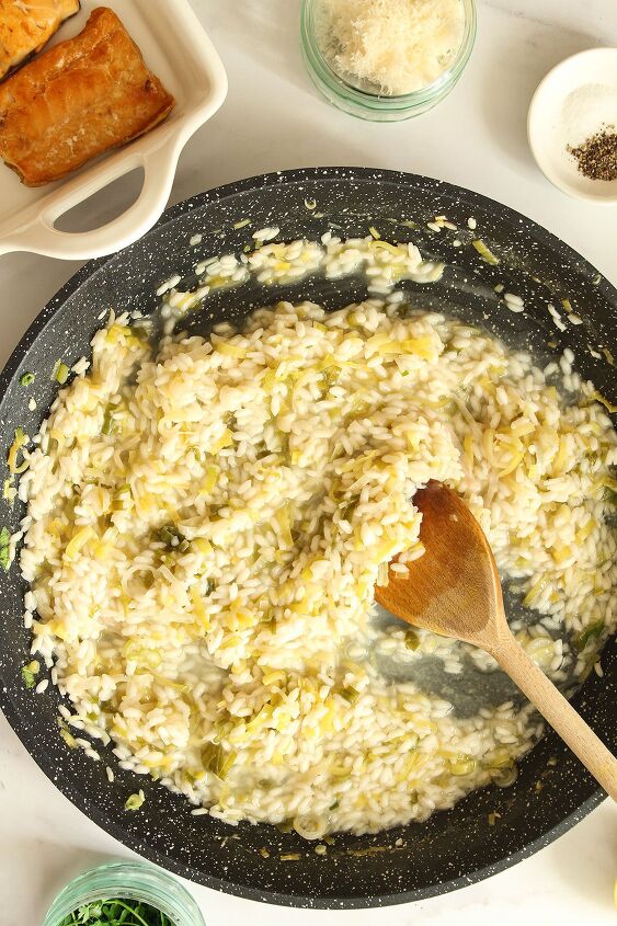 smoked haddock and leek risotto easy one pan recipe, Saut d leeks and spring onion scallions and rice with the stock added stirred with a wooden spoon in a dark coloured pan